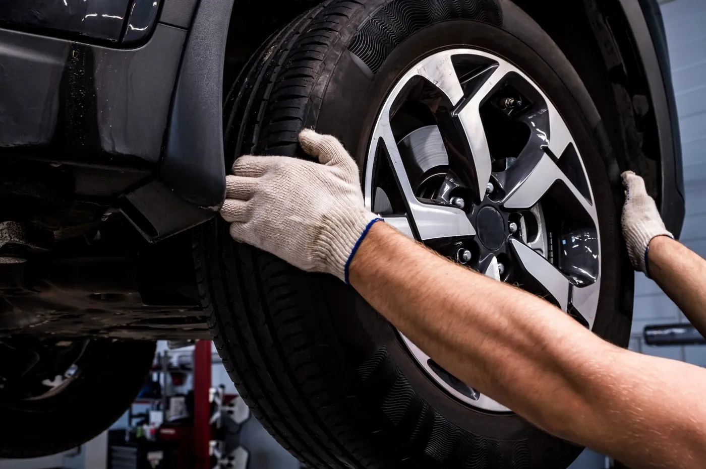 Mechanic removing a wheel to inspect worn brake pads and rotors