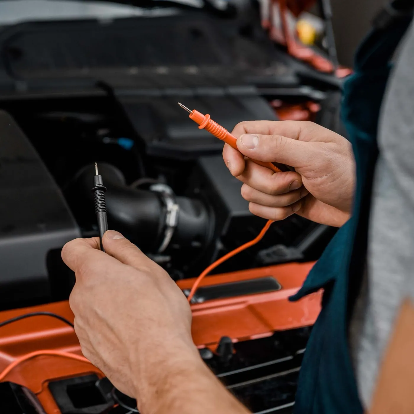 Mechanic testing a car battery and charging system with a multimeter